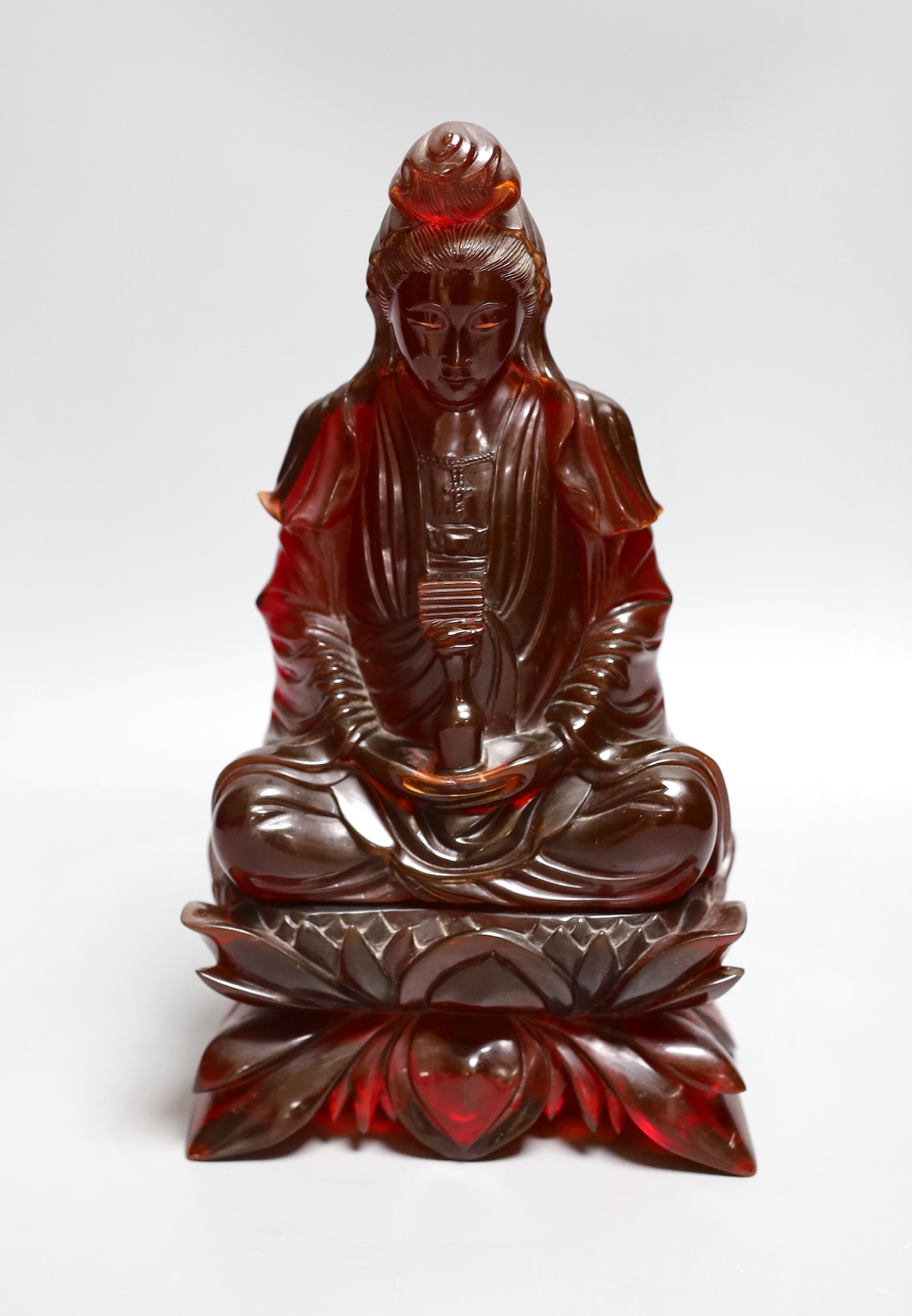 A Chinese ‘cherry amber’ phenolic seated figure of Guanyin, 29cms high